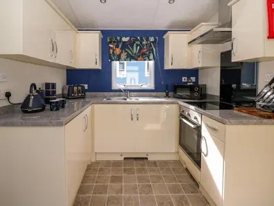a kitchen with white cabinets and a sink at 98 The Heron in New Quay
