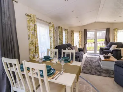 a dining room and living room with a table and chairs at 98 The Heron in New Quay