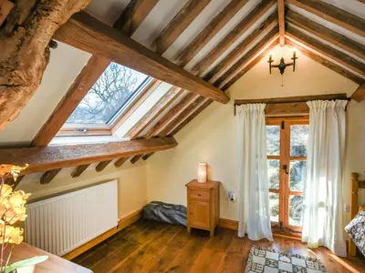 a room with a large window and wooden ceilings at Aberserw Cottage in Trawsfynydd