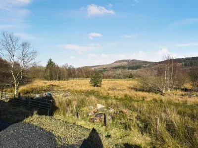 a field with a fence and a hill in the background at Aberserw Cottage in Trawsfynydd
