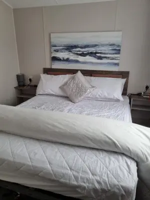 a bed with white sheets and pillows on it at Willerby Malton in Barmouth