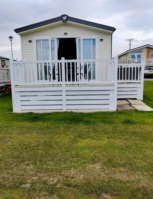 a small white house with a white fence at Willerby Malton in Barmouth