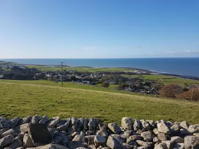 a field with rocks and the ocean in the background at POD1 Family Glamping with seaview & Wi-Fi in Llwyngwril