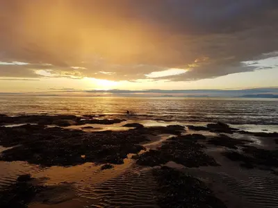 a sunset on the beach with the sun setting at POD1 Family Glamping with seaview & Wi-Fi in Llwyngwril