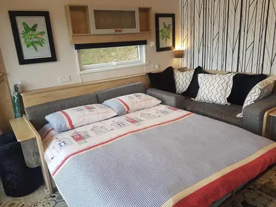 a living room with a couch and a bed at POD1 Family Glamping with seaview & Wi-Fi in Llwyngwril
