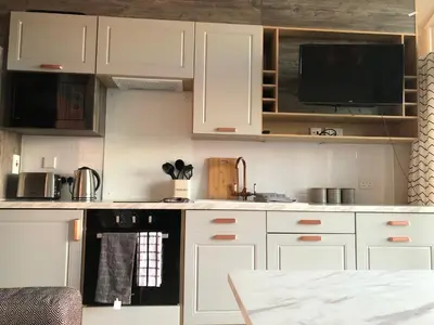 a kitchen with white cabinets and a black oven at POD1 Family Glamping with seaview & Wi-Fi in Llwyngwril