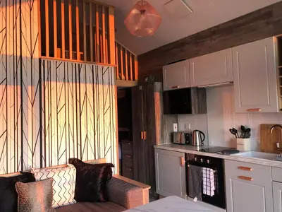 a living room with a couch and a kitchen at POD1 Family Glamping with seaview & Wi-Fi in Llwyngwril
