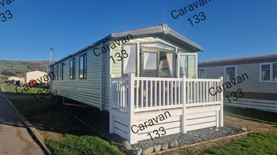 a green and white train car sitting in a yard at Caravan 133 snowdon summit 090 in Barmouth