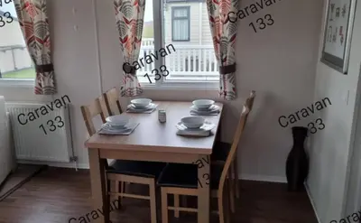 a dining room with a table and chairs and a window at Caravan 133 snowdon summit 090 in Barmouth