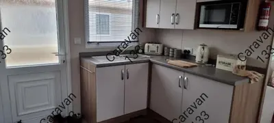 a kitchen with white cabinets and a sink and a window at Caravan 133 snowdon summit 090 in Barmouth