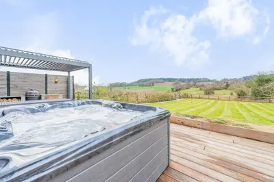 a hot tub on a deck with a view of a field at Tackroom Great Ness Shrewsbury in Great Ness