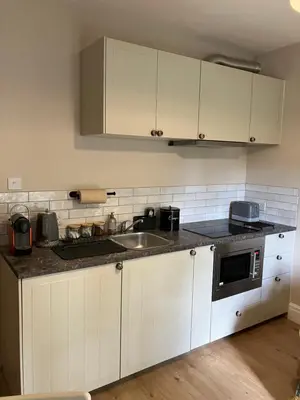 a kitchen with white cabinets and a sink at Broughshane in Church Stretton