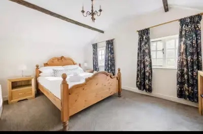 a bedroom with a wooden bed and a window at Bramble Cottage in Atcham