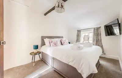 a bedroom with a large white bed and a mirror at Bramble Cottage in Atcham