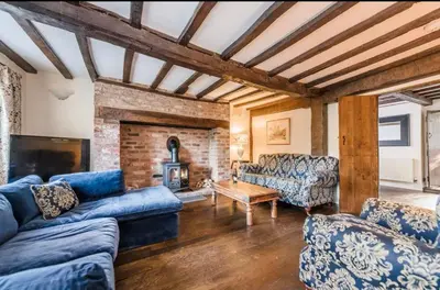 a living room with blue couches and a fireplace at Bramble Cottage in Atcham