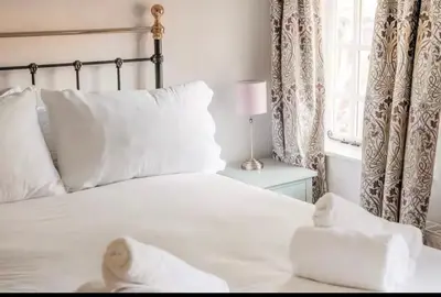 a bedroom with a white bed with white pillows and a window at Bramble Cottage in Atcham