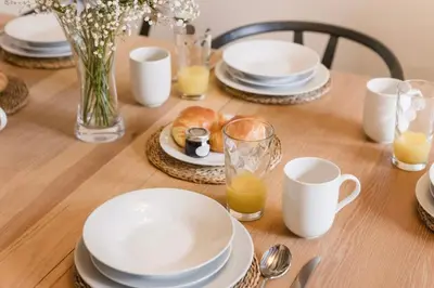 a wooden table with plates and cups of orange juice at Bramble Cottage in Atcham