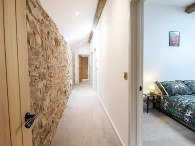 a hallway leading to a room with a stone wall at Threshers Barn in Oswestry
