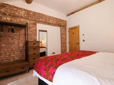 a bedroom with a bed and a brick wall at Threshers Barn in Oswestry