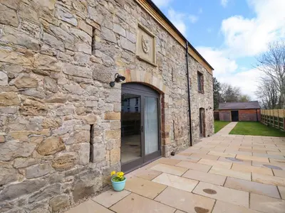 a stone building with a large glass door at Threshers Barn in Oswestry