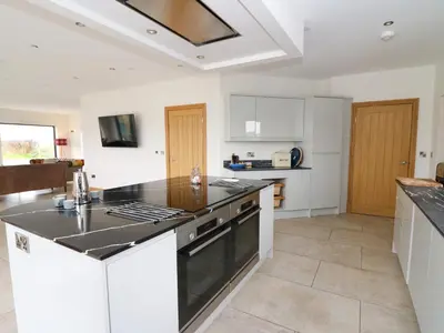 a kitchen with white cabinets and a black counter top at Rhandir Hen in Aberystwyth