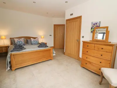 a bedroom with a wooden bed and a wooden dresser at Rhandir Hen in Aberystwyth