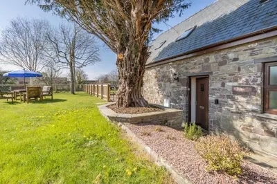 a stone house with a tree in the yard at 2 Bed in Llangorse oc-t30290 in Llangorse