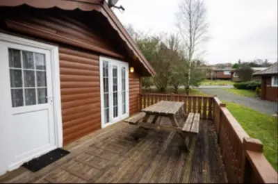 a wooden deck with a picnic table next to a building at 345 Ida's Cabin in Trawsfynydd
