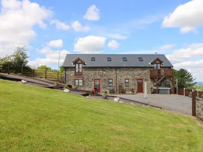 an old stone house with a grass field in front at Llwyngwinau Isaf Barn in Tregaron
