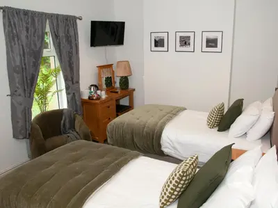 a bedroom with two beds and a chair and a television at Gwesty Seren Hotel in Blaenau-Ffestiniog