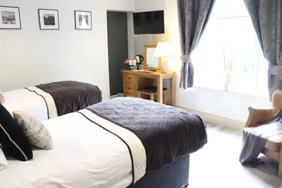 a bedroom with two beds and a desk and a window at Gwesty Seren Hotel in Blaenau-Ffestiniog