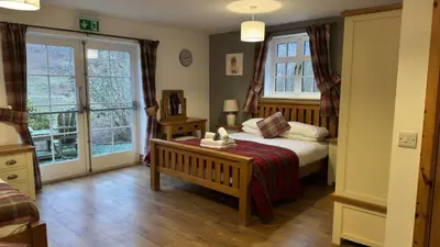 a bedroom with a bed and two windows at Ty Penbont House in Rhayader