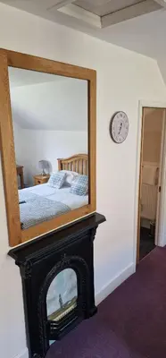 a mirror over a fireplace in a bedroom at Ty Penbont House in Rhayader
