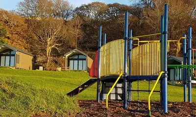 a playground with a slide in a park at POD2 Family Glamping with seaview & Wi-Fi in Llwyngwril