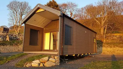 a tiny house sitting on top of a pile of rocks at POD2 Family Glamping with seaview & Wi-Fi in Llwyngwril