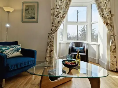 a living room with a glass table and a bowl of fruit at Green Hill ground floor Family Apartment in Barmouth