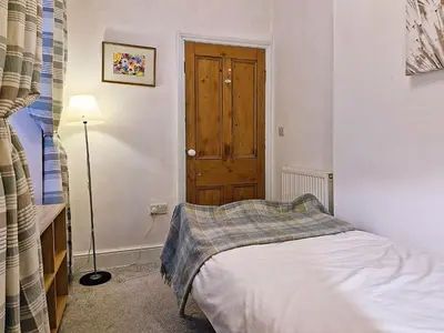 a small bedroom with a bed and a wooden door at Green Hill ground floor Family Apartment in Barmouth