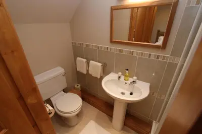 a bathroom with a toilet and a sink and a mirror at Tan-y-Graig at Snowdonia in Harlech