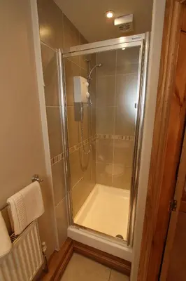 a shower with a glass door in a bathroom at Tan-y-Graig at Snowdonia in Harlech