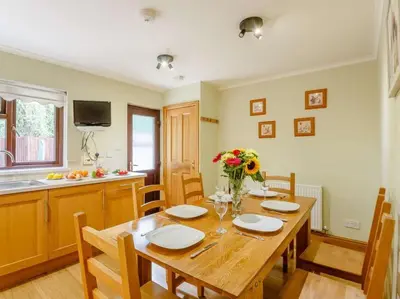 a dining room with a wooden table and a kitchen at Tan-y-Graig at Snowdonia in Harlech