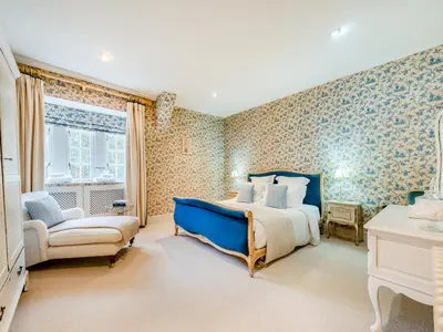 a bedroom with a blue bed and a chair at Gwynfryn in Llanarth