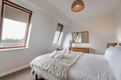 a bedroom with a bed with a white comforter and two windows at 3 Bed in Aberdovey oc-n29124 in Aberdyfi