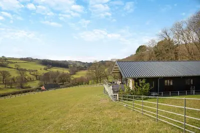 a farm house with a fence in a field at 4 Bed in Berriew oc-t31114 in Berriew
