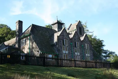 an old house with a fence in front of it at Elan Valley Lodge in Llanwrthwl