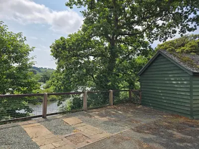 a green building next to a fence and a tree at The Loft at Box Bridge in Brecon