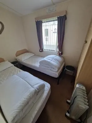two beds in a small room with a window at Ocean Breeze Hideaway 2 Bed Pet Friendly Static Caravan In Clarach Bay in Aberystwyth