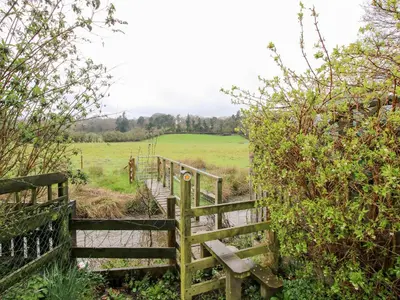 a wooden staircase leading into a field with a fence at The Millers Roost at Dudgeley Mill in Church Stretton