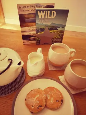 a table with a plate of food and cups of coffee at Relaxing Coastal Retreat for 2 Hot Tub Log Fire in Tywyn