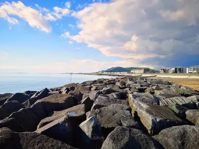 a group of rocks on a beach with the ocean at Relaxing Coastal Retreat for 2 Hot Tub Log Fire in Tywyn