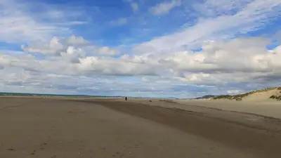 a person walking on a sandy beach at Relaxing Coastal Retreat for 2 Hot Tub Log Fire in Tywyn